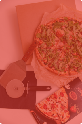 Pizza Voila ze świeżą rukolą, obok nóż do pizzy oraz menu